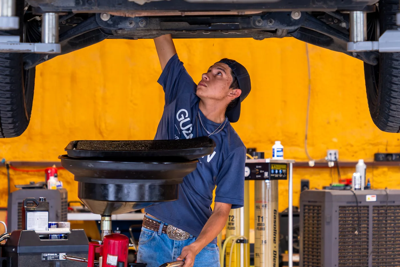 Guzman Automotive technician draining oil during an oil change